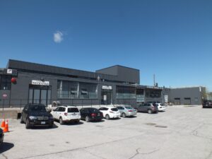 Front exterior of 100 Symes Road Toronto industrial building with loading docks, parking area, and industrial flex space in the Stock Yards District