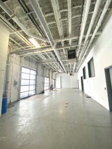 Common loading area at 100 Symes Road Toronto featuring drive-in loading doors, high ceilings, and industrial flex space