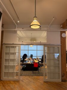 Boardroom office in Unit 100 at 20 Maud Street Toronto featuring glass sliding doors, exposed brick, timber beams, and hardwood floors