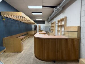 View from front entrance of Parkdale licensed café for sale at 1304 King St West Toronto, featuring wood service counter, built-in seating, and open café layout.