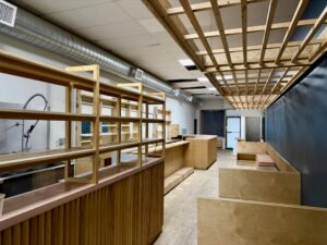 Rear view of Parkdale licensed café for sale at 1304 King St West Toronto, showing service counter, shelving, and seating layout toward front entrance.
